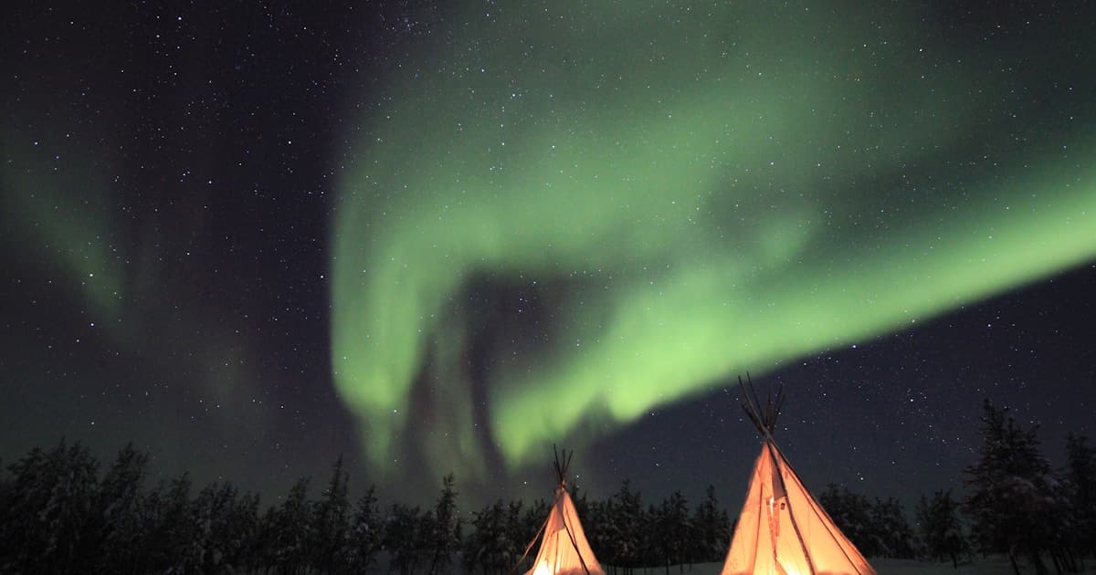 Illuminated tent under a curtain of northern lights in the Northwest Territories near Yellowknife