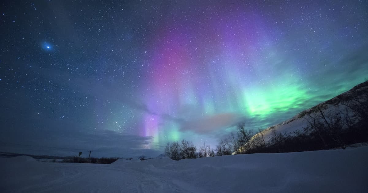 Multi-colored northern lights over snow-capped mountains in Tromsø, Norway