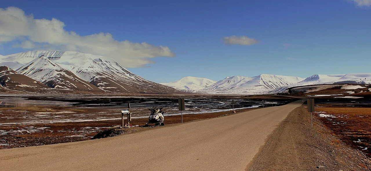 Road leading towards snow-streaked mountains near Longyearbyen in June daylight